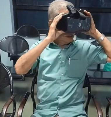 An elderly patient holding the InSight VR headset to his eyes in a clinic waiting area